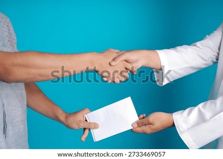 Close-up Hands Handshake While Receiving Envelope on Blue Background