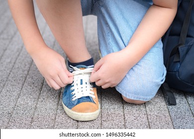 Closeup hands of a healthy preteen school boy tying shoelaces of his blue canvas sneakers and ready to go. Back to school, Everyday life, Preparation, Teenager style, Confidence Tween concept.