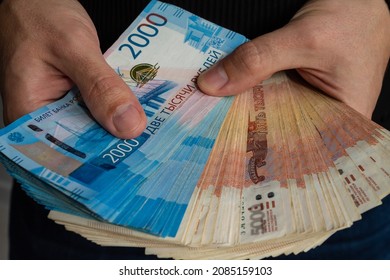 Close-up hands hold a wad of Russian money two thousand bills