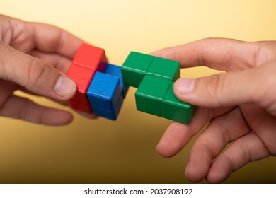 A Closeup Of The Hands Holding Colorful Pieces Of Block Puzzle 