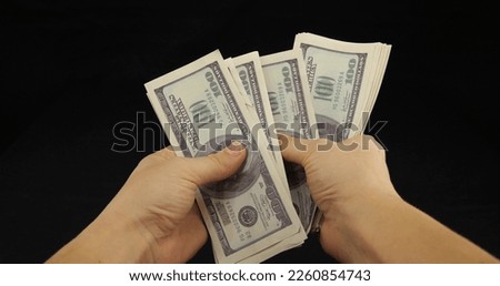 Close-up. Hands holding a fan of one hundred dollar bills on a black background. Win concept. Dollar banknotes in hands on a black background isolated.