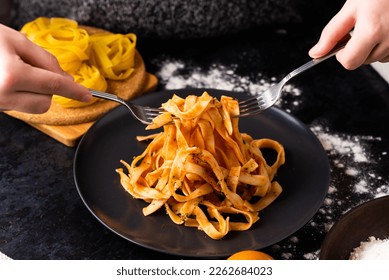 A close-up of hands holding fork, digging into a plate of fast food in a kitchen. - Powered by Shutterstock