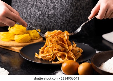 A close-up of hands holding a fork, digging into a plate of fast food in a kitchen. - Powered by Shutterstock