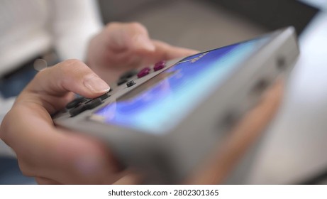 Close-up of hands holding game controller, gaming on mobile phone nearby