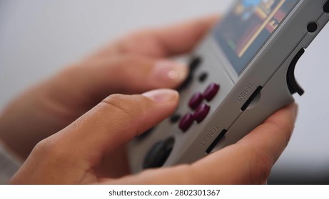 Close-up of hands holding game controller, gaming on mobile phone nearby