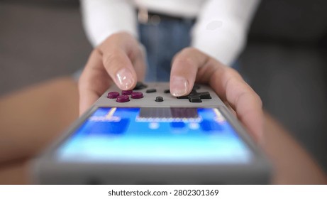 Close-up of hands holding game controller, gaming on mobile phone nearby