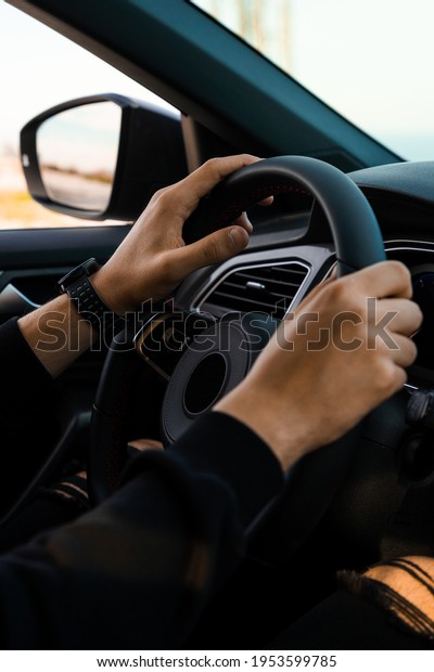 Close-up of\
hands holding the handlebars of a car, wearing a smart watch on the\
wrist. Wearing dark, modern\
clothes.