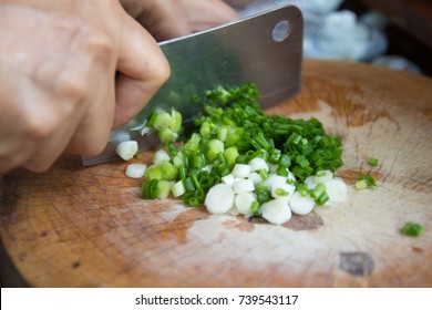 Closeup hands holding knife chopping, cutting green onion, scalliion. Sliced with knife on wooden cutting board. Chopped fresh spring onion.
Cooking vegetables in kitchen. Ingredients for Thai foods. - Powered by Shutterstock