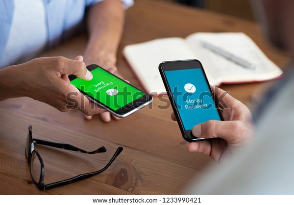 Closeup hands holding mobile phone with application\
for send and receive money. Man and woman holding smartphone and\
making payment transaction. Smart phone screen displaying payment\
sent.