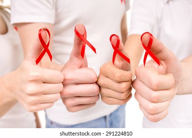 Close-up Of Hands Holding Red Ribbons To Rise AIDS HIV Awareness.