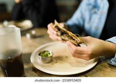 Close-up of hands holding a tasty quesadilla filled with meat at a taco shop, enjoying authentic mexican cuisine - Powered by Shutterstock