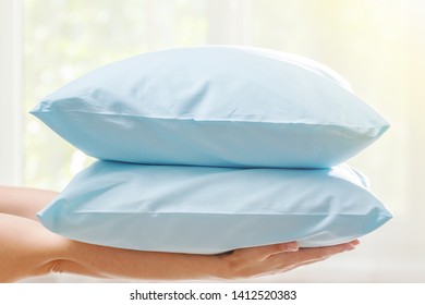 Closeup Of Hands Holding Two Blue Pillows, On Blurred Background.