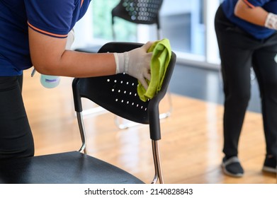 Close-up Hands Of Housekeeper Cleaning Chair In Meeting Room Prevention Of Corona Virus 2019 Or Covid 19 Infection, Protection Against The Corona Virus. Save And Clean In Public Building