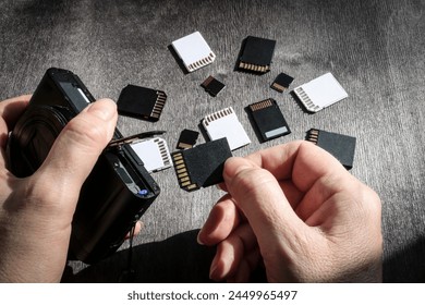 Close-up of hands inserting a memory card into the camera's memory slot, with SD and MicroSD flash cards in the background