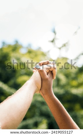 Close-up of the hands of an interracial couple interlocking their fingers.