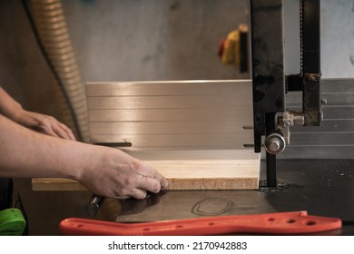 Close-up Hands Of Joiner, Professional Man Hands Using Panel Sizing Saw Woodworking Machine Or Tool, Knife Sawing To Cut Wood Board In Small Shop. Red Pusher, Tappet On The Table. Workshop Or Garage