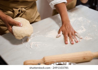 Close-up of hands kneading dough on a floured surface. The image captures the process of preparing homemade bread or pizza in a cozy kitchen setting. - Powered by Shutterstock