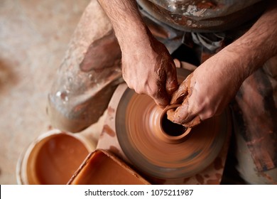 Close-up hands of a male potter in apron making a vase from clay, selective focus - Powered by Shutterstock