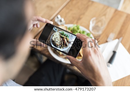 Close-up of hands male in the restaurant taking picture food with his smart phone
