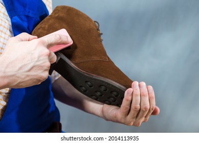 Closeup of Hands of Male Shoes Cleaner with Special Brush For Suede Derby Chukka BootsWhile Working in Workshop. Horizontal Image