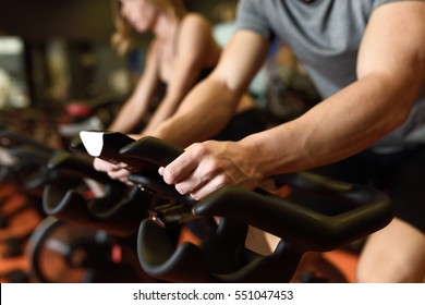 Close-up of hands of a man biking in the gym, exercising legs doing cardio workout cycling bikes. Couple in a spinning class wearing sportswear. - Shutterstock ID 551047453