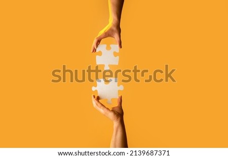 Closeup hands of man connecting jigsaw puzzle. Two hands trying to connect couple puzzle with yellow background. Hand connecting jigsaw puzzle. Man hands connecting couple puzzle piece