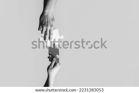 Closeup hands of man connecting jigsaw puzzle. Business solutions, success and strategy concept. Black and white. Two hands trying to connect couple puzzle with yellow background.