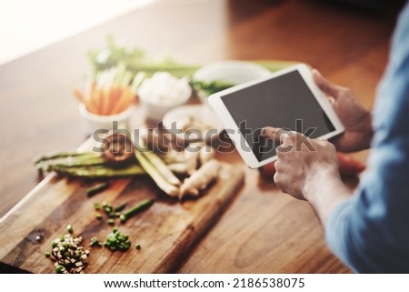 Closeup of hands of man holding a tablet to research healthy recipes, watch cooking tutorial videos and scrolling online for meal ideas while making dinner, lunch or breakfast. Man browsing on app
