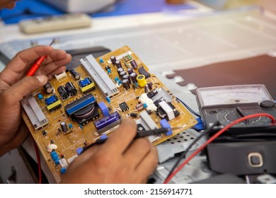 Close-up Of Hands Man Technician Repairing A Television. Repairman Are Checking Television Circuit Board With Multimeter. TV Repair Service Center