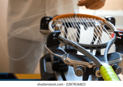 close-up of the hands of a master who pulls the strings on a tennis racket using a special machine