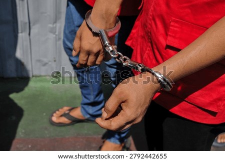 Close-up of a prisoner’s hands in modern handcuffs while being escorted to court.