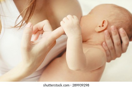 Closeup hands, mother feeding breast baby at home