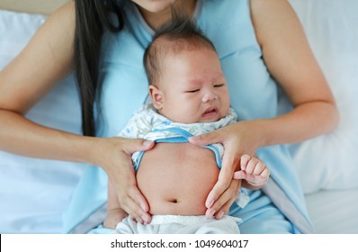 Close-up Hands Of Mother Touching And Take Care Infant With Pain In Her Stomach.