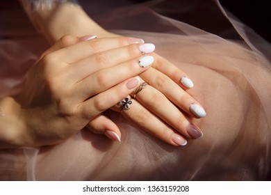 Close-up hands with a neat french manicure. Rings on the fingers. Gentle fresh morning hands.
