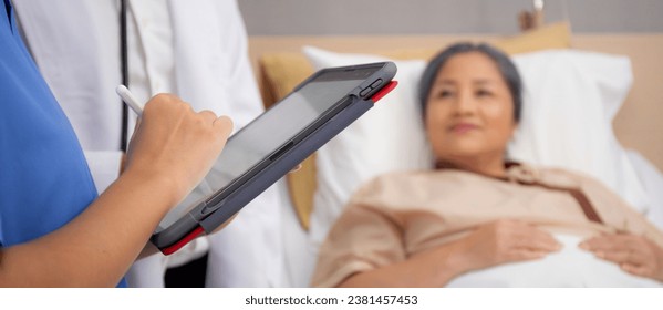 Closeup hands nurse writing report medical and health care on tablet while specialist doctor explaining and check and diagnostic with elderly patient in hospital, examining disease, senior and unwell. - Powered by Shutterstock