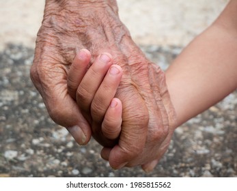 Close-up of hands of old man and child holding each other. Grandfather and grandson connection, two generations, love