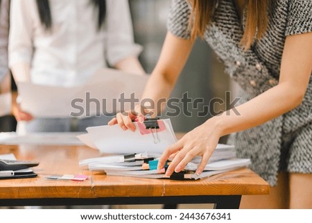 Close-up of hands organizing a stack of documents with colorful binder clips on a wooden table