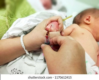 Closeup Hands Of Pediatric Nurse Using IV Catheter Stab On Sick Newborn Baby Hand And Drained His Blood To Blood Tube For To Checkup Glucose And All Virus In His Blood At NICU Wards.