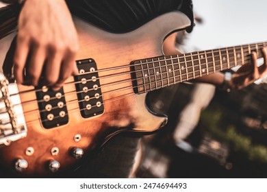 Close-up of hands playing a bass guitar during an outdoor performance. - Powered by Shutterstock