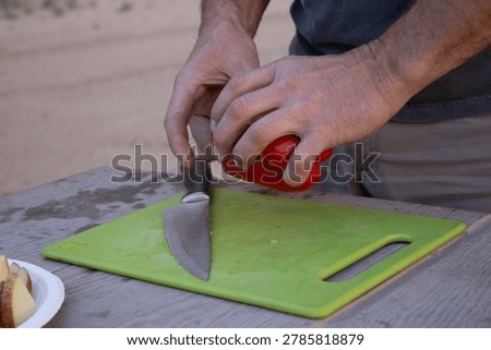 Close-up of hands preparing red bell pepper on cutting board during outdoor campsite cooking and camping lifestyle experience.