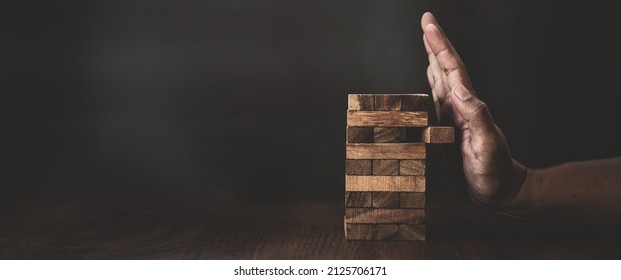 Close-up Hands Prevent Tower Stacked With Caution To Prevent Collapse Or Crash Concepts Of Financial Risk Management And Strategic Planning.