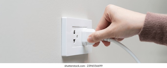 Close-up hands pull off electronic device plug after finish used.
