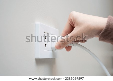 Close-up hands pull off electronic device plug after finish used.