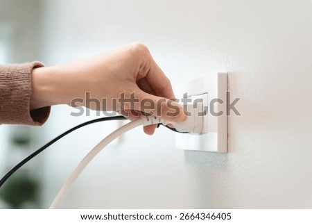 Close-up hands pull off electronic device plug after finish used.