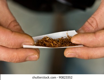 A Closeup Of Hands Rolling Tobacco.