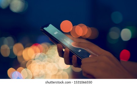 Close-up of hands scanning fingerprint on smartphone to unlock mobile phone on bokeh colors light in night atmospheric city, Concept security in identity technology.