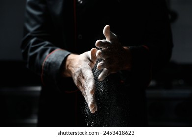 Close-up of a chef’s hands scattering fine white flour, with a dark culinary backdrop - Powered by Shutterstock