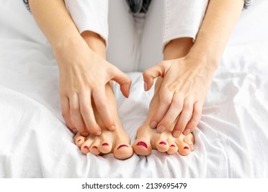 Close-up Of Hands Scratch Legs Sitting On White Bed At Home. Itchy Skin, Fungus, Fungal Bacterial Infection, Allergic Reaction, Eczema, Dermatitis Of The Foot. Health And Skincare Concept.