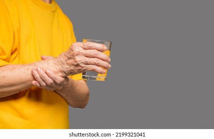 Close-up Of Hands Senior Woman Trying To Hold A Glass Of Water. Causes Of Hand Shaking Include Parkinson's Disease, Stroke, Or Brain Injury. Mental Health Neurological Disorder