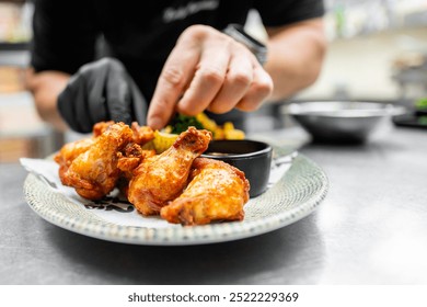 A close-up of hands serving crispy fried chicken drumsticks on a white plate, garnished with fresh herbs and accompanied by a dipping sauce. Perfect for food blogs, menus, or culinary articles.